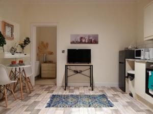 ein Wohnzimmer mit einem TV und einem Tisch in der Unterkunft The Lottbridge in Eastbourne