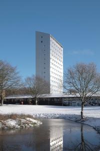 un edificio alto con un reflejo en el agua en Højhuset Kulturhotel, en Herning
