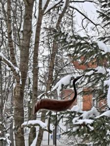 a bird statue covered in snow next to trees at Dworek Na Równi in Zakopane