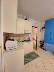cocina con armarios blancos y microondas en Monolocale IL GRIFO, en Albisola Superiore