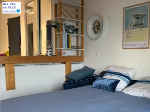 een slaapkamer met een bed, een spiegel en een plank bij Studio Mezzanine La vie en bleu- Vue mer Deauville in Deauville