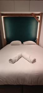 - un lit blanc avec une tête de lit et des oreillers verts dans l'établissement CŒUR MENOU, Radis'son & PARKING, à Nantes