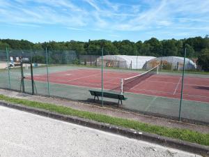 a tennis court with a bench on a tennis court at La Haute Bédinière in Crouy-sur-Cosson