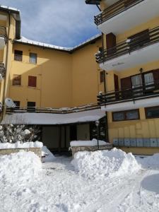 um edifício com neve empilhada no chão em Elle house Mansarda em Rocca di Cambio