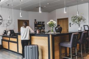 a woman standing at a bar with her luggage at The More Hotel Lund in Lund