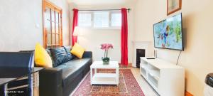 un soggiorno con divano in pelle nera e tavolo di Flat 2, 6 Tauton Mews in Marylebone a Londra