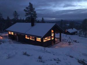 una cabaña de madera en la nieve por la noche en Myrullen - Cabin at Sørbølfjellet, en Flå