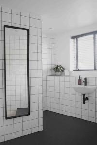 a white tiled bathroom with a mirror and a sink at Blackett Street Bunkhouse in Leeds