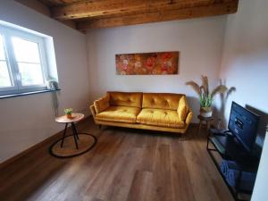 ein Wohnzimmer mit einem gelben Sofa und einem TV in der Unterkunft Ferienwohnung Lindele 