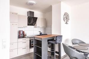 a kitchen with white cabinets and a table and chairs at TOP 60qm Eigentumswohnung Neuss/DüsseldorfMesseKÖ in Neuss