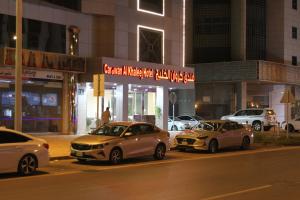 tres autos estacionados en un estacionamiento por la noche en Carawan Al Khaleej Hotel Olaya en Riad