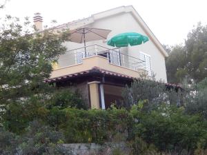 a white house with an umbrella on the balcony at Apartments Mimose in Milna