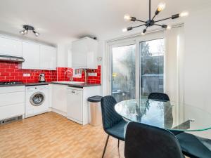 a kitchen with a glass table and chairs at Pass the Keys Stylish 4 Bedroom Home with Parking in Borehamwood in Borehamwood