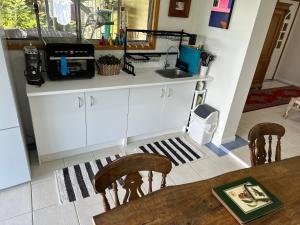 a kitchen with white cabinets and a table with a microwave at Slice of Heaven at Number 7, privacy and views in Tweed Heads