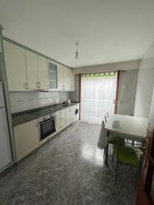 uma cozinha com armários brancos e uma mesa em A casiña do Rodri em Ribadavia
