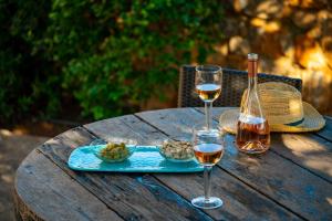 uma mesa de madeira com dois copos de vinho e uma garrafa em Carob Cottage em Elounda