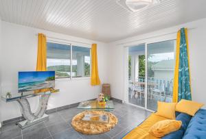 La Villa Bleue Topaze 1er - Vue Mer في مدينة لو فوكلين: غرفة معيشة مع أريكة زرقاء وتلفزيون