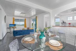 La Villa Bleue Topaze 1er - Vue Mer في مدينة لو فوكلين: غرفة طعام مع طاولة وكراسي زجاجية
