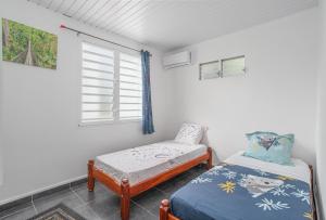 La Villa Bleue Topaze 1er - Vue Mer في مدينة لو فوكلين: غرفة نوم بسرير مزدوج ونافذة