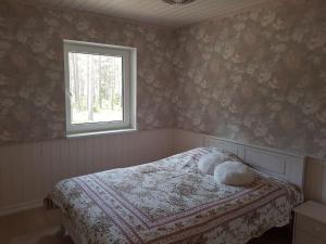 a bedroom with a bed with a blanket and a window at Puraviku puhkemaja in Elbiku