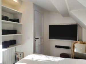 Schlafzimmer mit einem Bett und einem Flachbild-TV an der Wand in der Unterkunft MARAIS CHIC heart of Paris, premium location ! in Paris