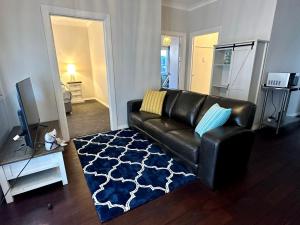 a living room with a black leather couch and a blue rug at Beach Shack Bunbury in Bunbury