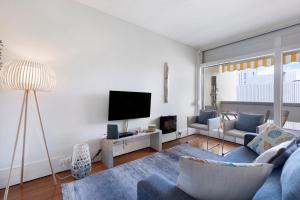 a living room with a blue couch and a tv at Apartamento T1 - Tróia Resort in Troia