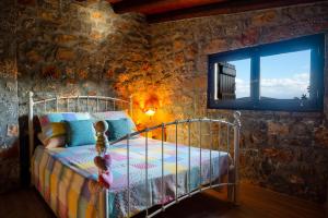 a bedroom with a bed in a stone wall at Carob Cottage in Elounda