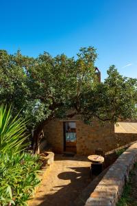 a brick building with a tree and two tables at Carob Cottage in Elounda