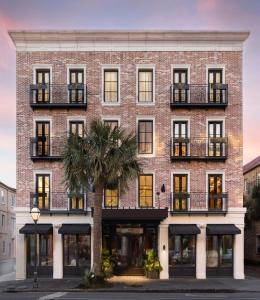 a brick building with a palm tree in front of it at The Palmetto Hotel, Charleston in Charleston