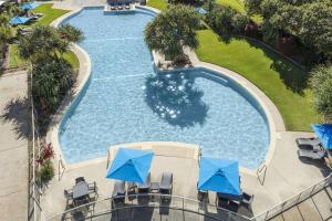 an overhead view of a swimming pool with blue umbrellas at Ramada By Wyndham Marcoola Beach in Marcoola