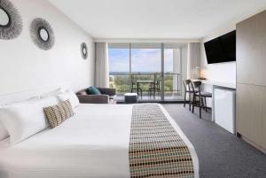 a hotel room with a large bed and a living room at Ramada By Wyndham Marcoola Beach in Marcoola