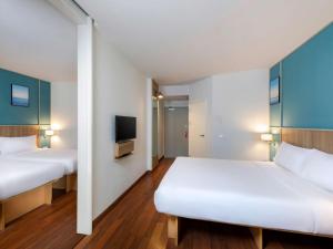 a hotel room with two beds and a tv at Hotel Ibis Samui Bophut in Bophut