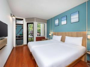 a bedroom with a large white bed and a tv at Hotel Ibis Samui Bophut in Bophut