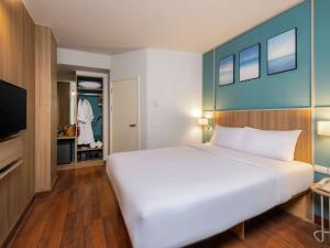 a bedroom with a large white bed and a tv at Hotel Ibis Samui Bophut in Bophut
