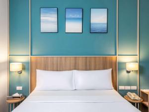 a bedroom with a bed and three pictures on the wall at Hotel Ibis Samui Bophut in Bophut