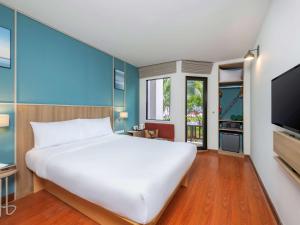 a bedroom with a large white bed and a flat screen tv at Hotel Ibis Samui Bophut in Bophut