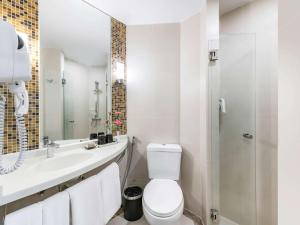 a white bathroom with a toilet and a sink at Hotel Ibis Samui Bophut in Bophut