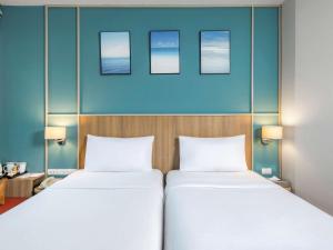 two beds in a room with three pictures on the wall at Hotel Ibis Samui Bophut in Bophut