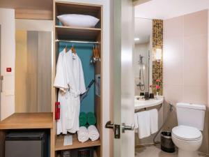 a bathroom with a white robe hanging on a door at Hotel Ibis Samui Bophut in Bophut