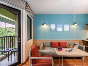 a living room with a couch and a table with a laptop at Hotel Ibis Samui Bophut in Bophut