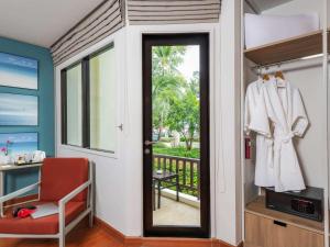 a room with a door and a chair and a balcony at Hotel Ibis Samui Bophut in Bophut