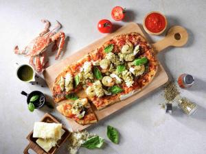 a pizza on a cutting board on a table at Hotel Ibis Samui Bophut in Bophut