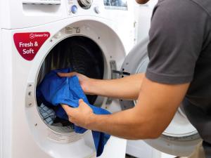 a person putting a cloth into a washing machine at Hotel Ibis Samui Bophut in Bophut