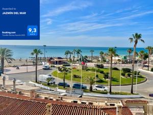 uma vista para um parque de estacionamento com palmeiras e o oceano em JAZMÍN DEL MAR em Torremolinos