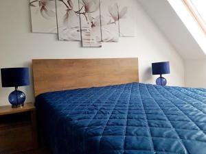 a bedroom with a blue bed and two lamps at Flowers in the attic in Żywiec