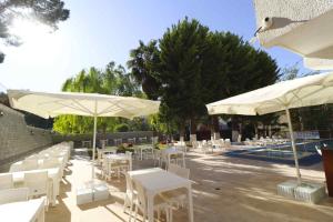 eine Terrasse mit weißen Tischen, weißen Stühlen und Sonnenschirmen in der Unterkunft Marla Didim Otel in Didim