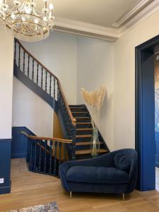a living room with a blue couch and a staircase at La Villa Barbieux in Roubaix