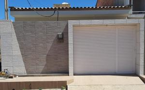 eine Garage mit einer weißen Garagentür auf einem Backsteingebäude in der Unterkunft Casa em São Miguel dos Milagres in São Miguel dos Milagres