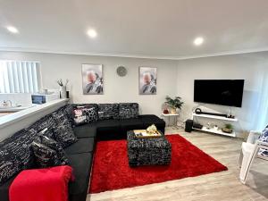 a living room with a black couch and a red rug at Beachside Townhouse Bunbury in Bunbury